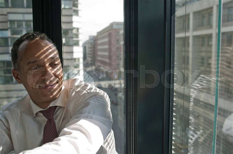 Man leaning at window smiling, stock photo
