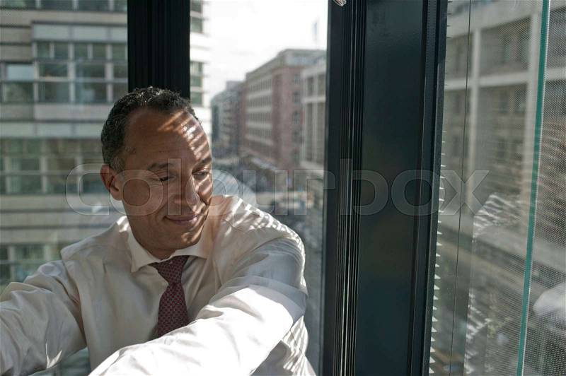 Man leaning at window smiling, stock photo