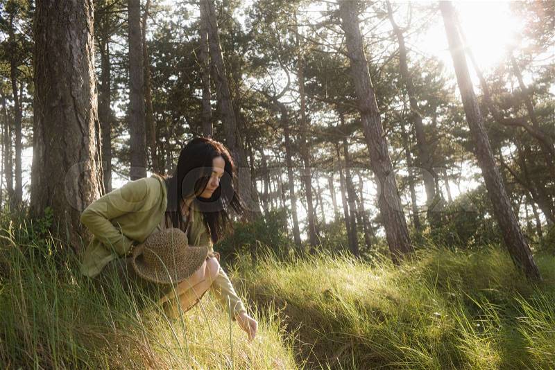 Woman crouching engaging in nature, stock photo
