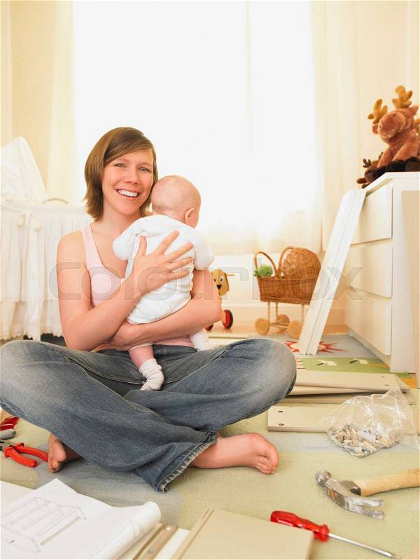 Woman with baby building furniture, stock photo