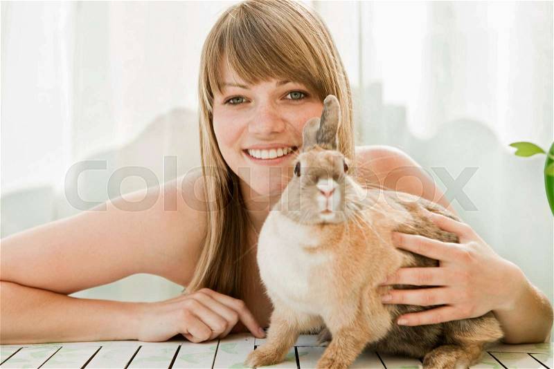 Young woman and a pet rabbit on a patio, stock photo