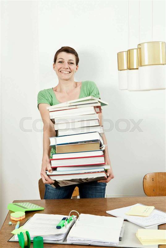 Female student carrying stack of books, stock photo