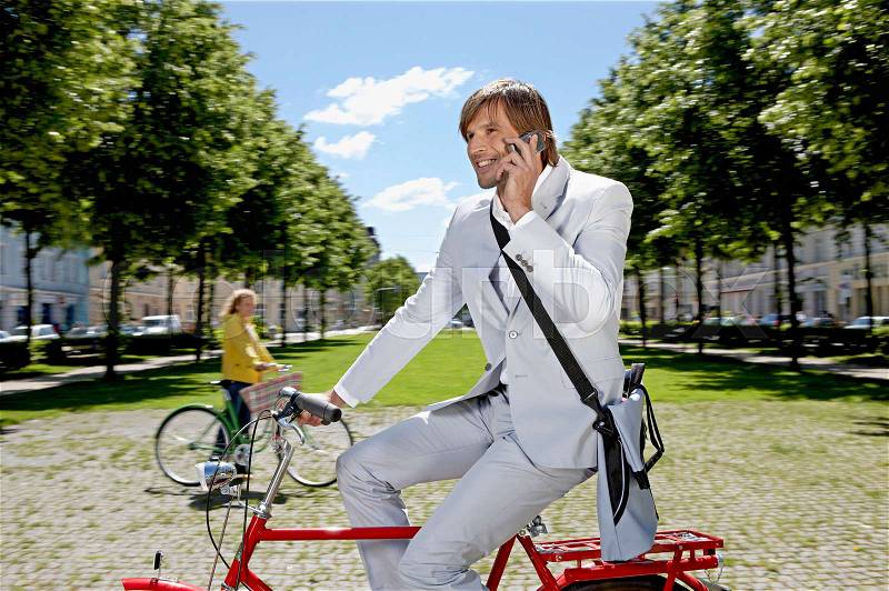 Man bicycling, talking on the phone, stock photo
