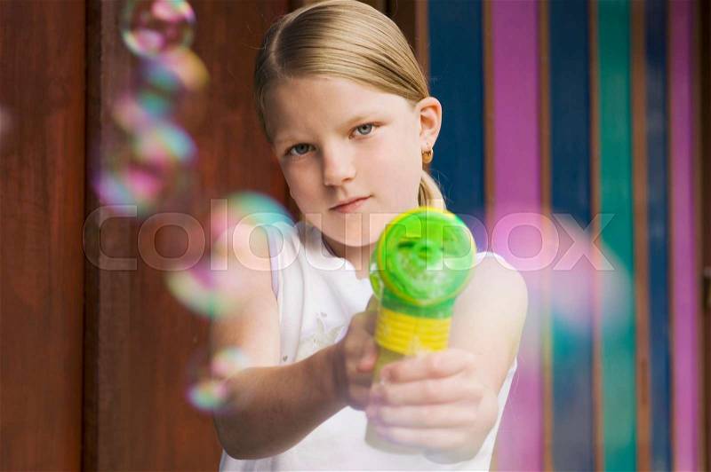 Girl pointing bubble gun to camera, stock photo