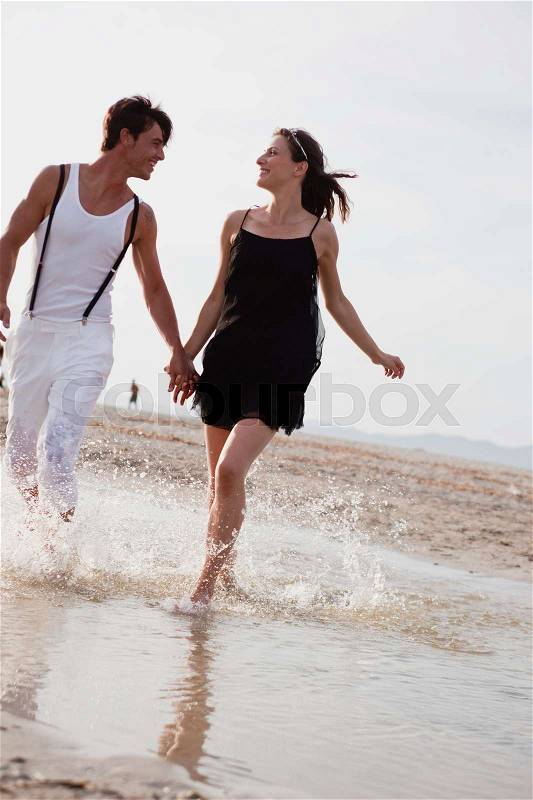 Couple running along the beach, stock photo