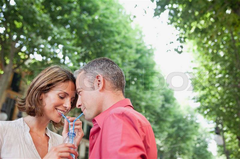 Couple drinking out same glass, stock photo