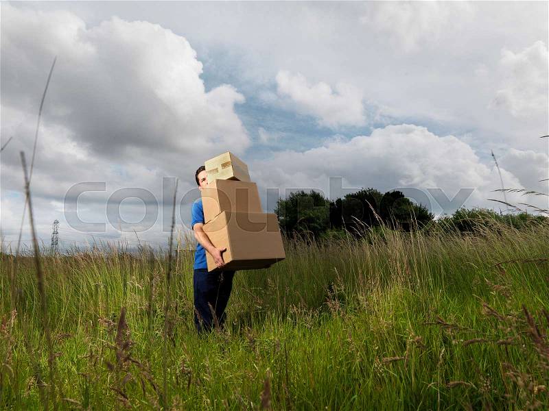 Man carrying boxes through field, stock photo