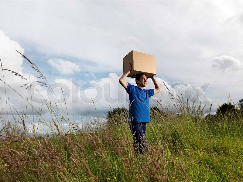 Man carrying boxes through field, stock photo