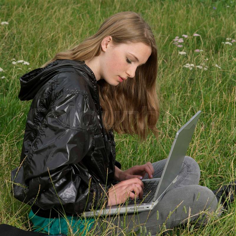 Young woman with laptop in the park, stock photo