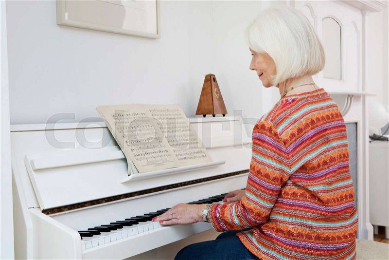 A senior female playing the piano, stock photo