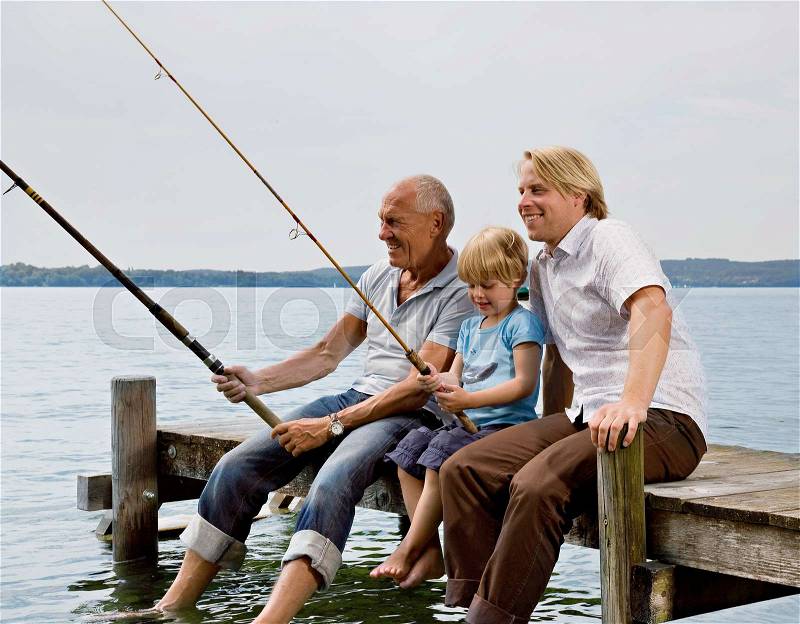 Boy fishing with grandfather, father, stock photo