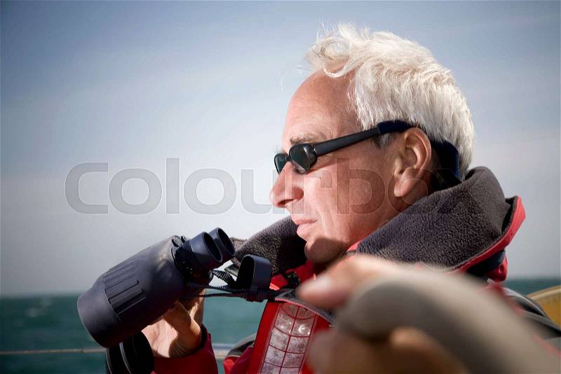 Man with binoculars sailing, stock photo