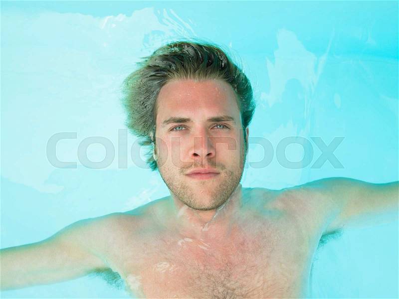 Young man floating in water, stock photo