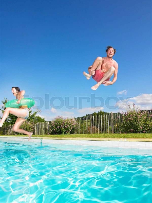People jumping into pool, stock photo
