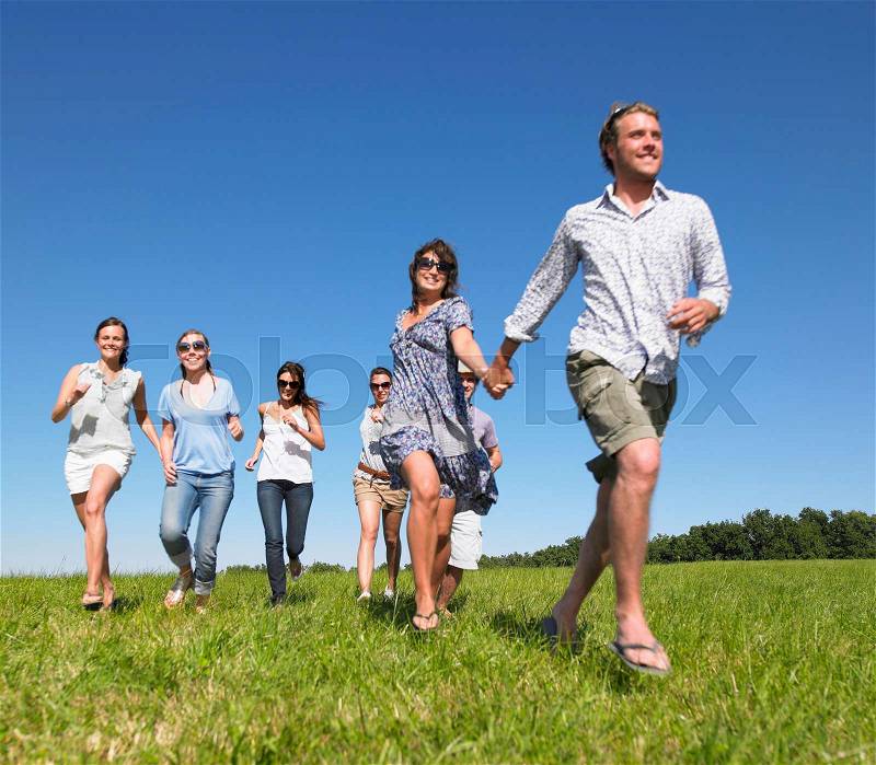Group of young people running in field, stock photo