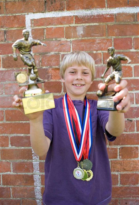 Child footballer with medals and trophy, stock photo