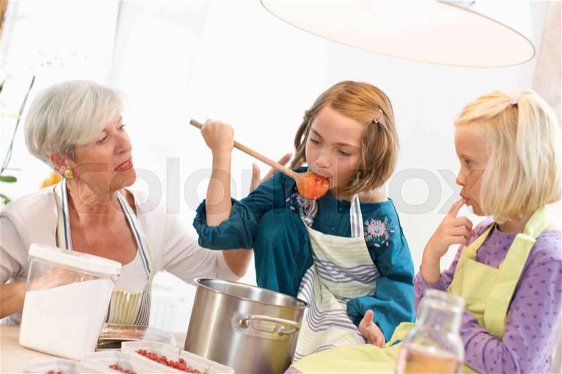Girls with grandmother cooking jam, stock photo