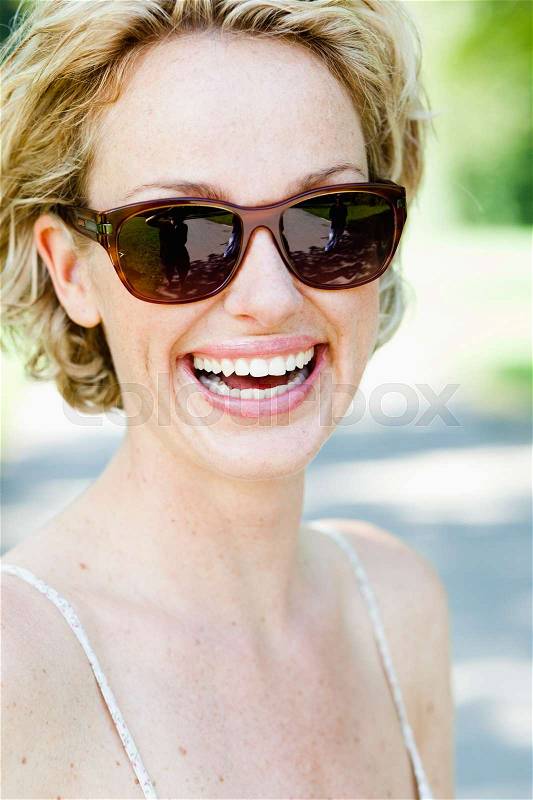 Woman with sunglasses smiling at viewer, stock photo