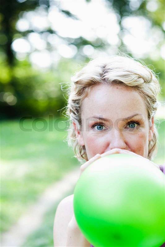 Woman blowing up balloon, stock photo