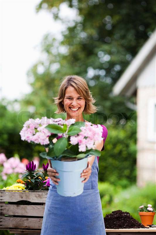 Woman offering a bucket of flowers, stock photo