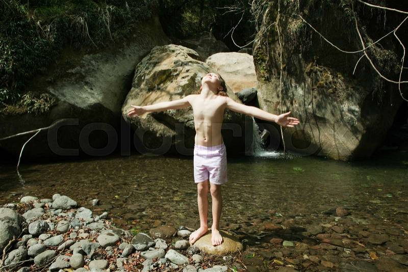 Girl standing on rock in stream, stock photo