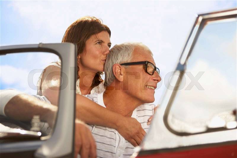 Senior couple embracing in sports car, stock photo