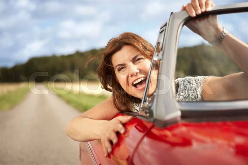 Mid aged woman in sports car, stock photo
