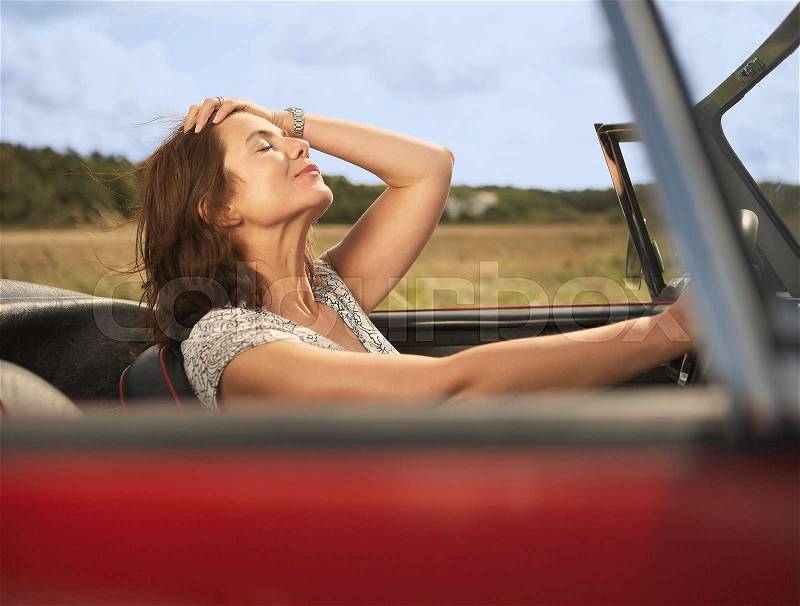 Mid aged woman in sports car, stock photo