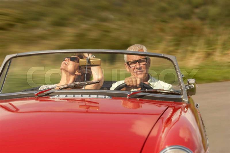 Mid aged couple in sports car, stock photo