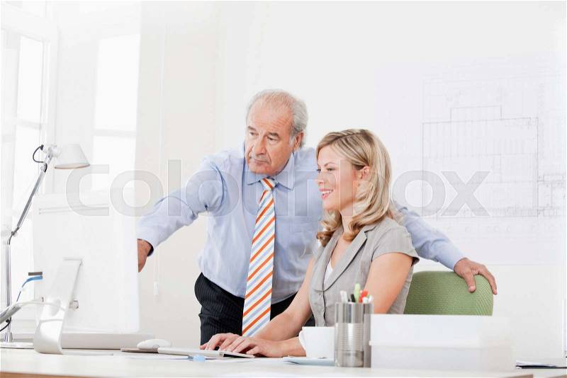 Senior and co-worker at a computer, stock photo