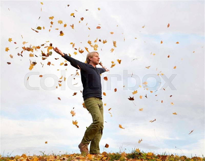 Man walking through flying autumn leaves, stock photo