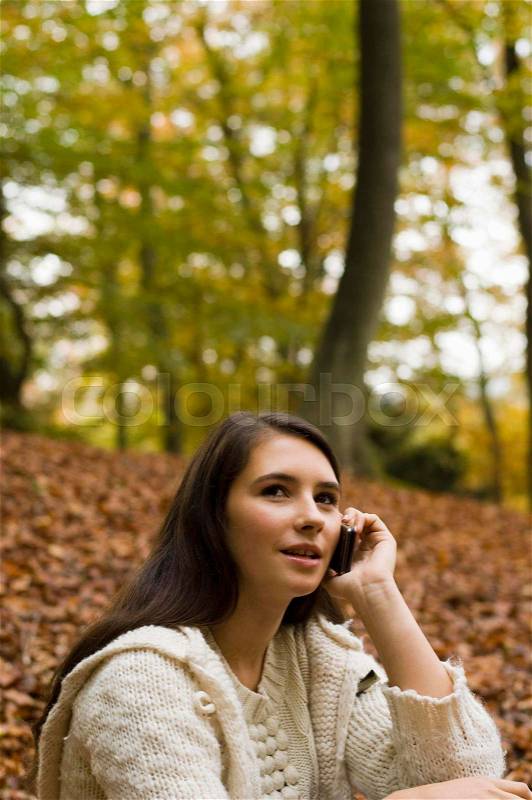 Girl on phone in woods, stock photo