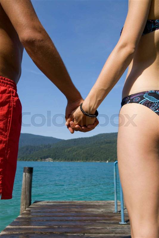 A couple holding hands by a lake, stock photo