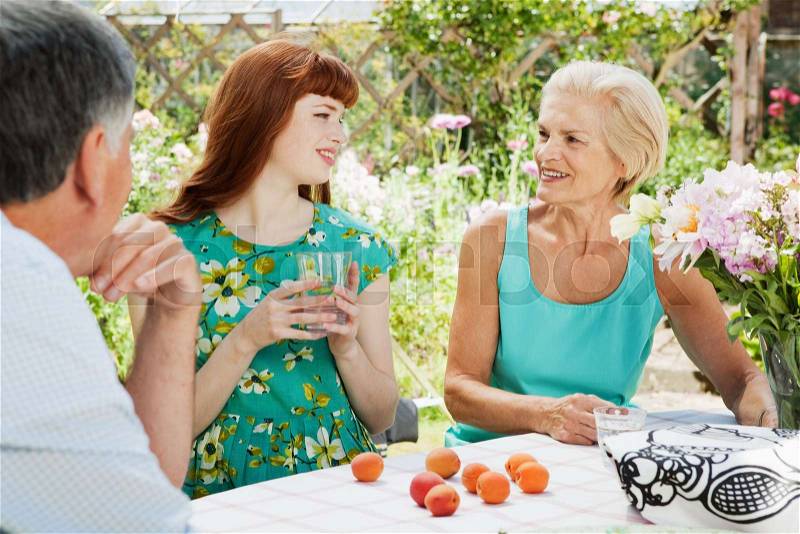 Woman talks with mature couple in garden, stock photo