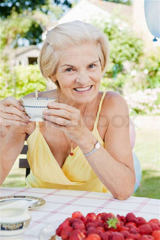 Mature woman with cup of tea, smiling, stock photo