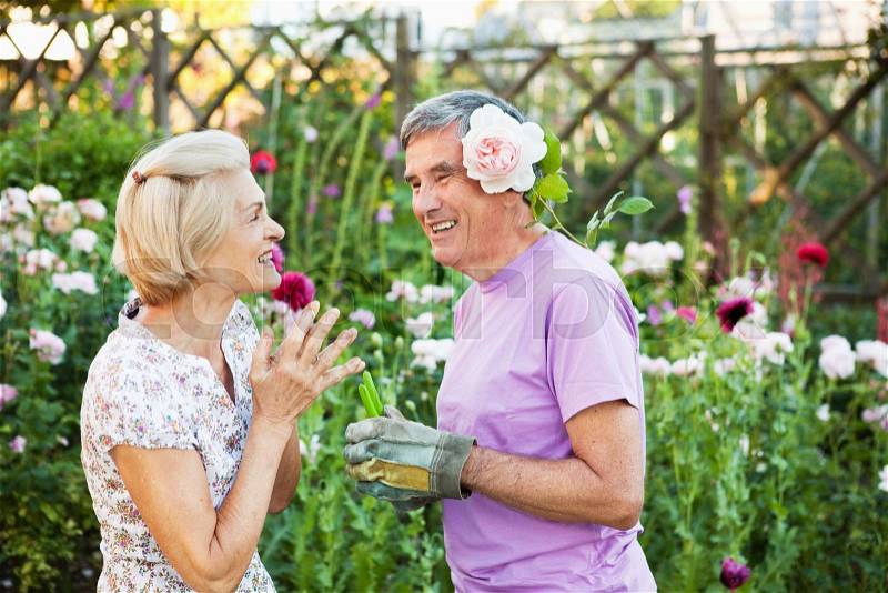 Woman laughs at man with rose behind ear, stock photo