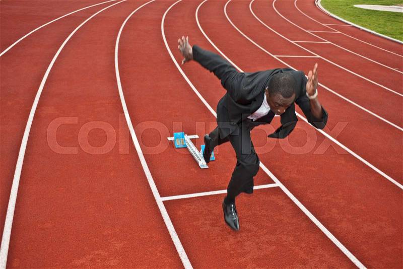 Businessman sprinting on running track, stock photo