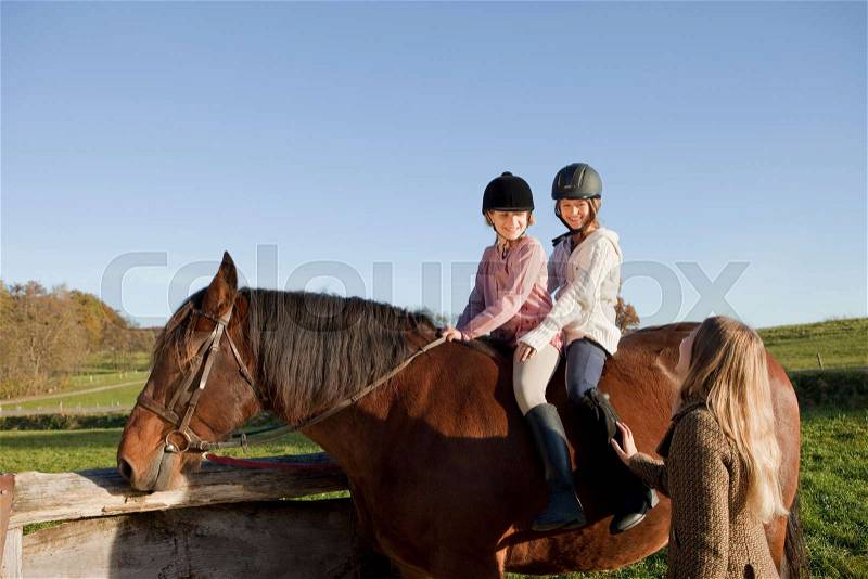 Woman talking with two girls on a horse, stock photo