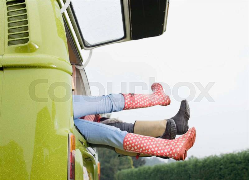 Legs sticking out of back of camper van, stock photo