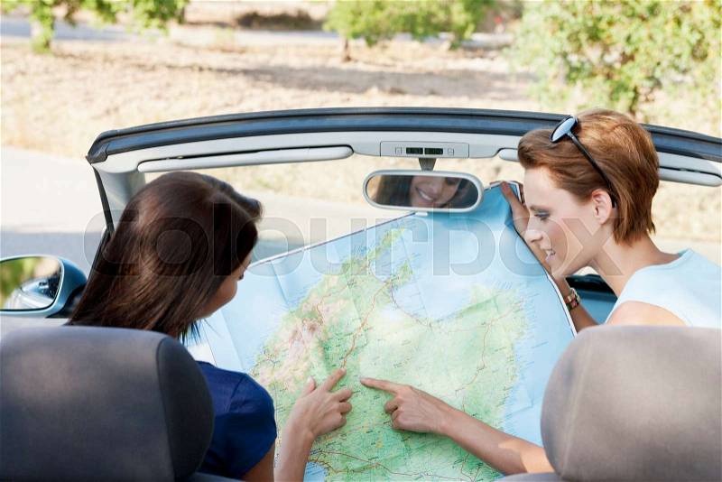 Two women reading a map in a car, stock photo