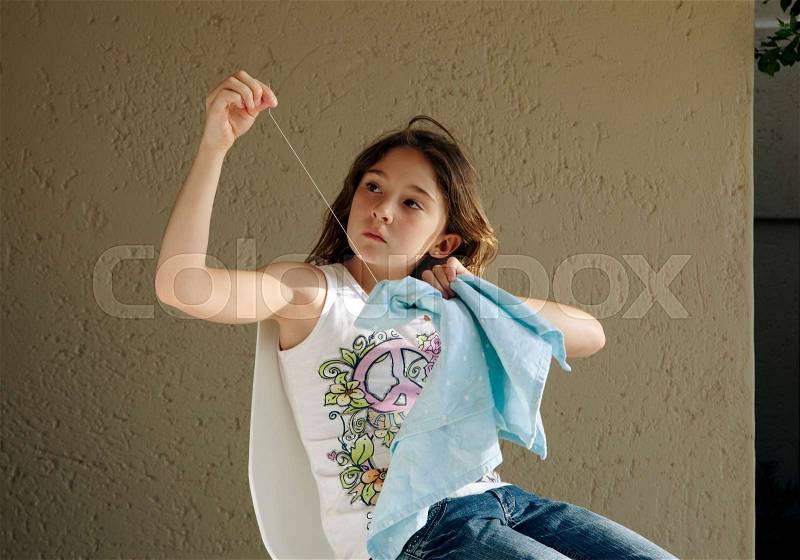 Girl learning to sew, stock photo