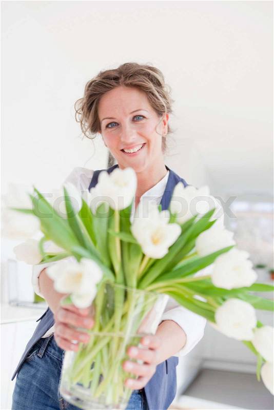 Woman holding a vase with white tulips, stock photo