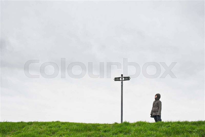 Woman looking up at sign post, stock photo