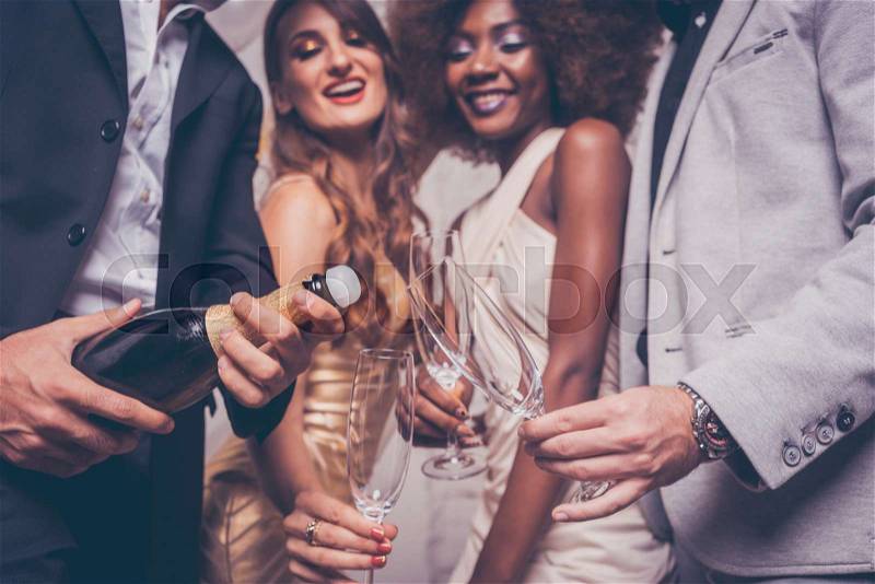 Man opening champagne bottle on celebration for new years eve or birthday in club, stock photo