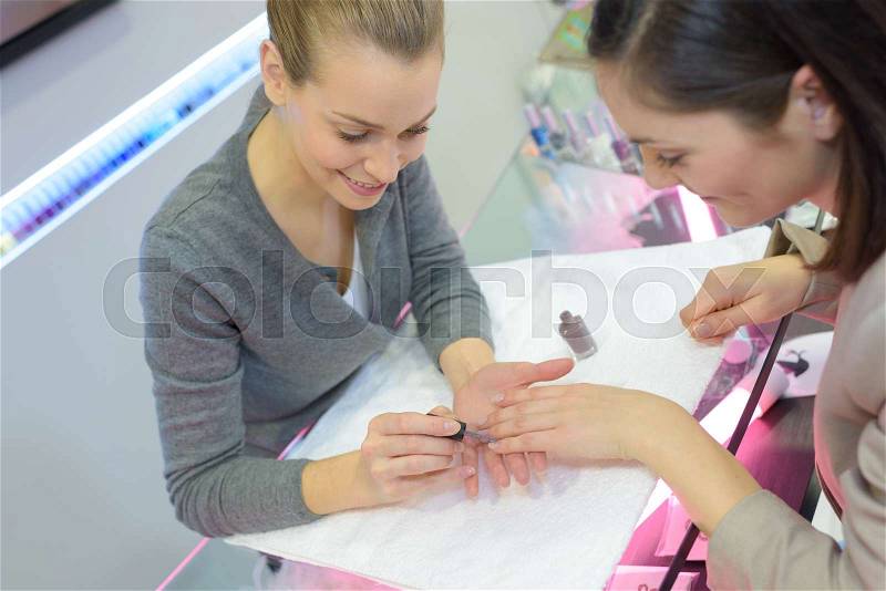 Nail salon worker giving a manicure to customer, stock photo