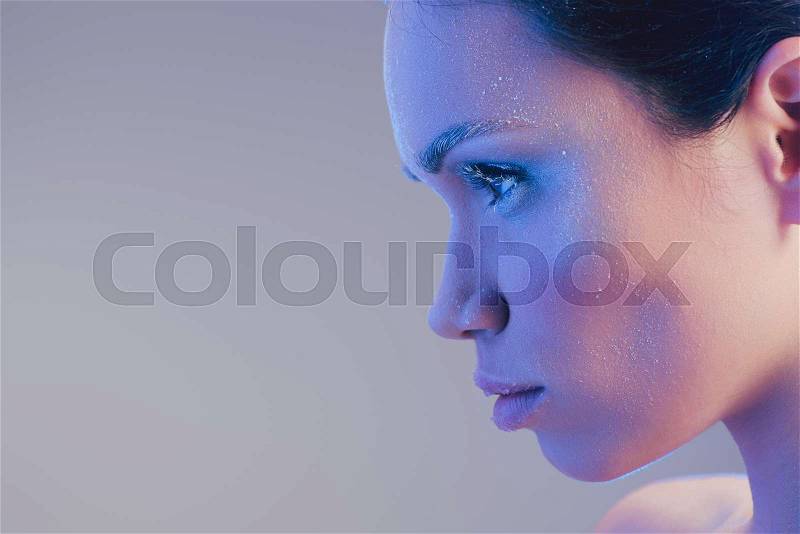 Side view shot of young woman with natural makeup and face covered in frost, stock photo