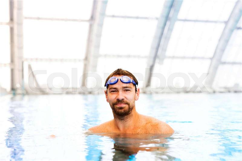 Man swimming in an indoor swimming pool. Professional swimmer practising in pool, stock photo