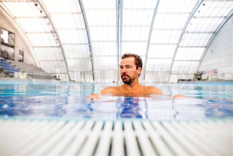 Man swimming in an indoor swimming pool. Professional swimmer practising in pool, stock photo