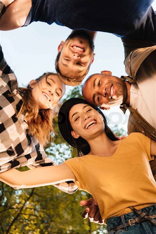 Bottom view of happy multicultural friends standing in circle, stock photo