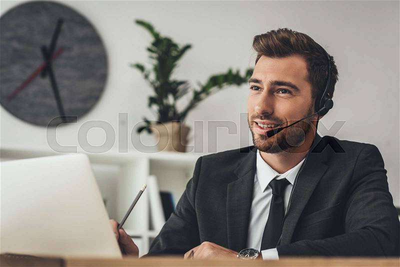 Handsome young call center worker talking by mike, stock photo